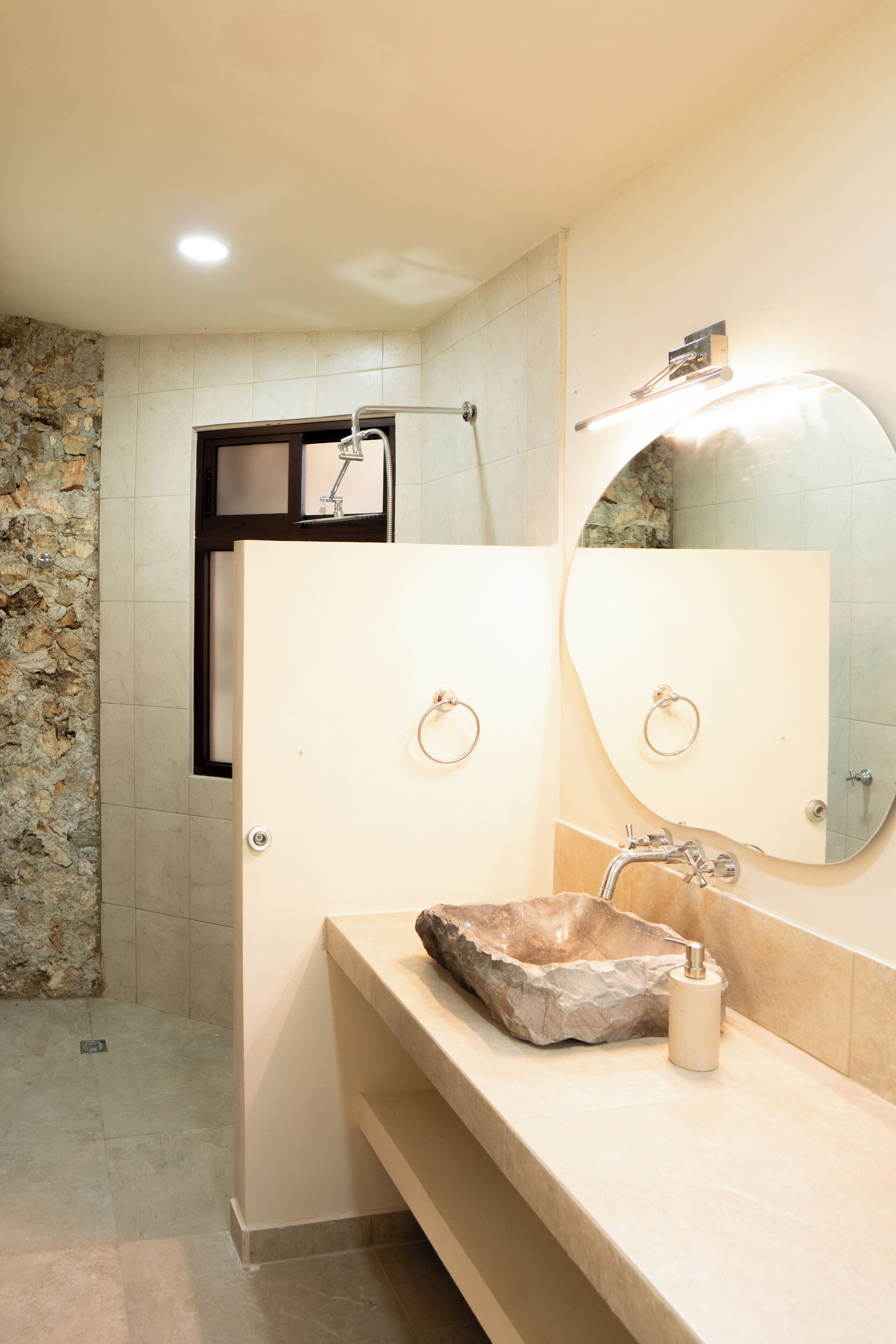Une salle de bain avec un lavabo en pierre, un miroir et un espace douche.