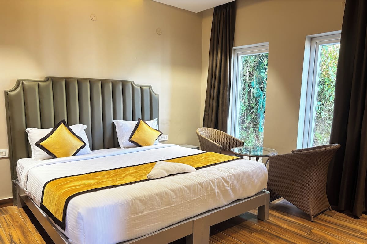 A hotel room with a large bed, a small table, and two chairs.