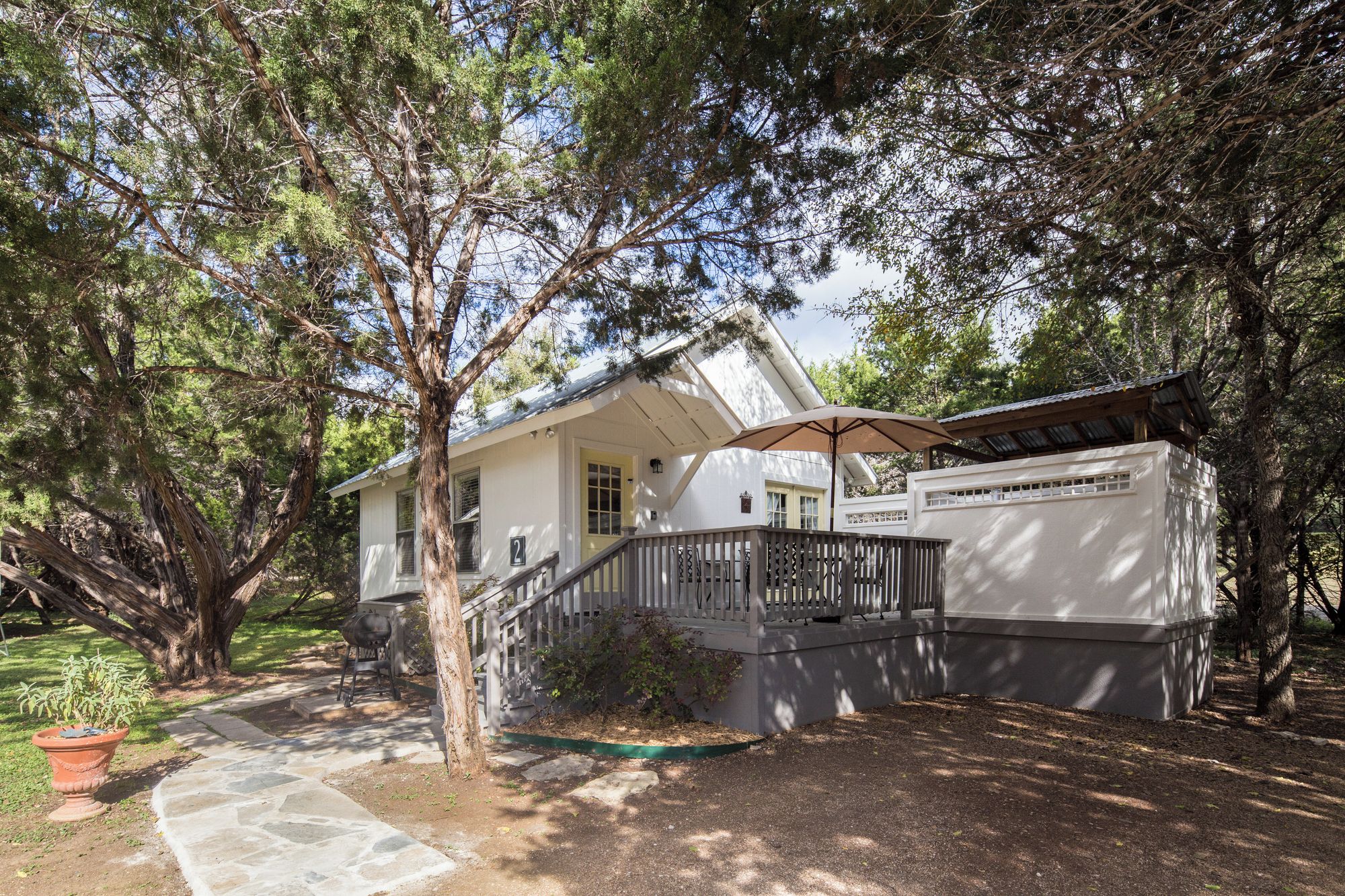 A two-story house with a porch, a covered patio, and a stone pathway leading to the entrance.