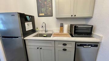 A compact kitchen with a refrigerator, sink, toaster, and dishwasher.