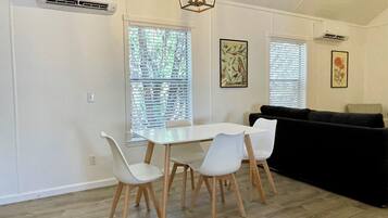 A dining area with a white table and chairs, a black sofa, and a ceiling light fixture.