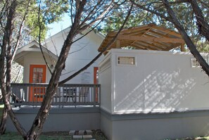 A building with a white exterior, a wooden roof structure, and a fenced outdoor area with a bench.