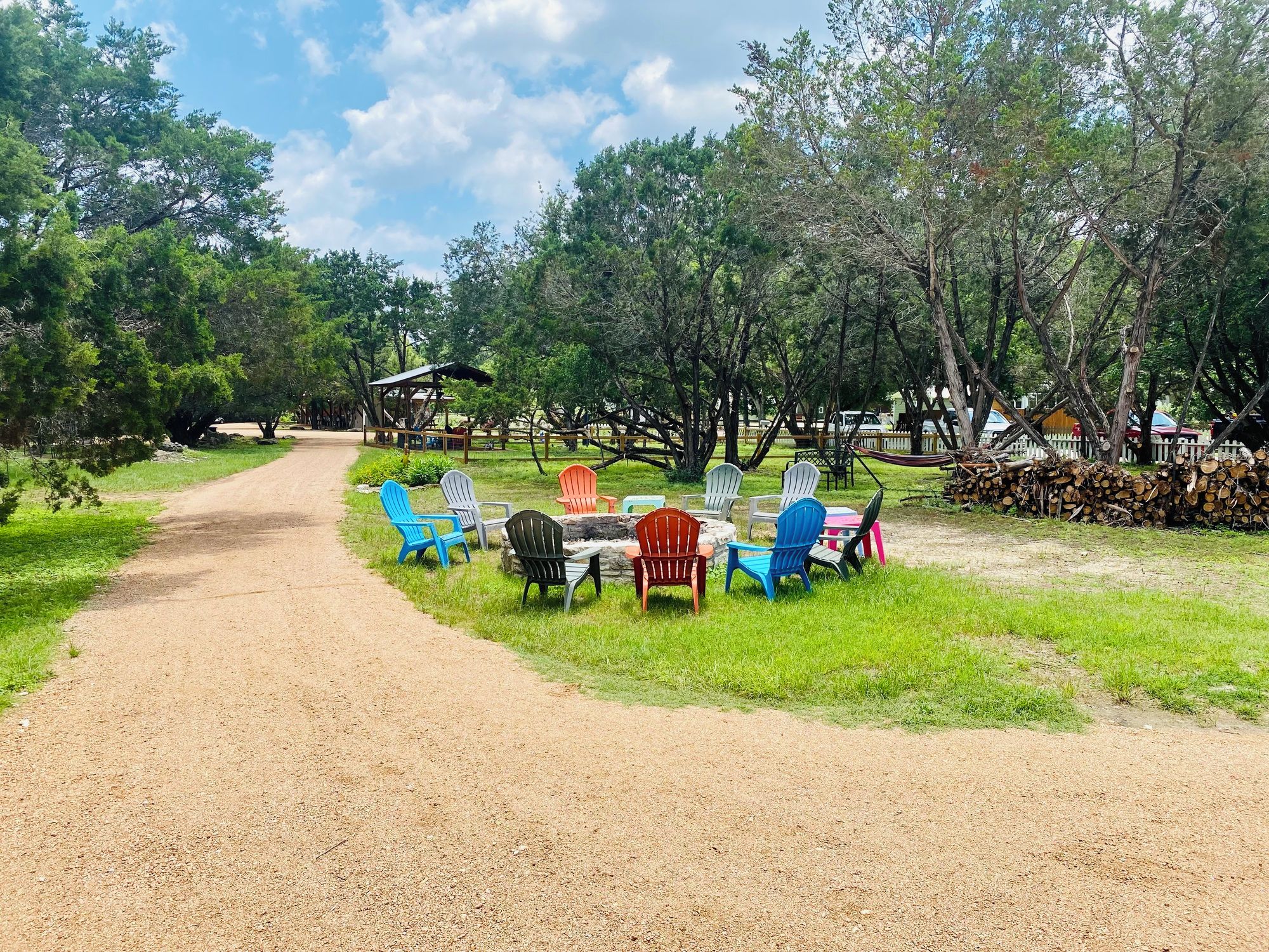 A gravel path leading to a grassy area with outdoor seating and a covered structure.