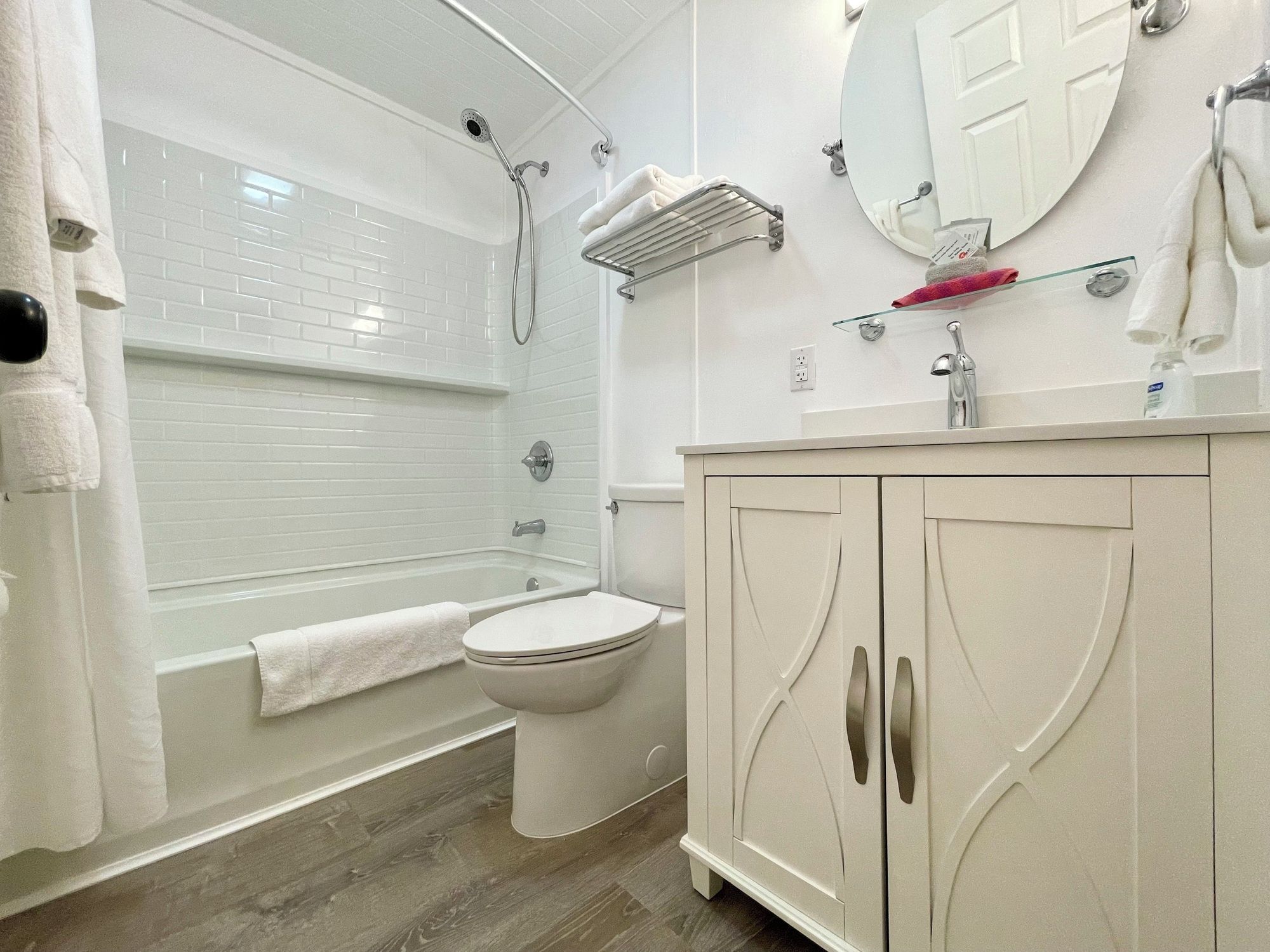 A bathroom with a bathtub, toilet, and vanity with a mirror.