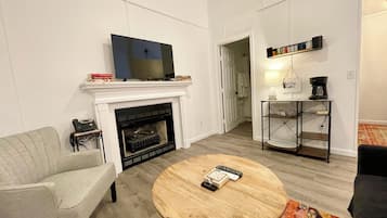 A living room with a fireplace, a television, a coffee table, and a sofa.