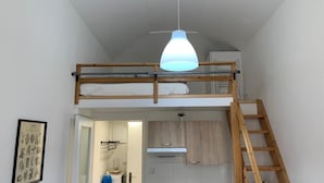 Ein Schlafzimmer im Loft-Stil mit Etagenbett, Holzleiter und Pendelleuchte.