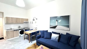 Ein kompakter Wohnraum mit Küchenzeile, Essbereich und einer Couch mit Blick auf einen Leuchtturm.