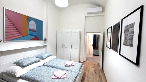 Ein Schlafzimmer mit Bett, Kleiderschrank, einem Gemälde und einem Flur zu einem weiteren Raum.
