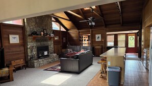 A log cabin interior with a stone fireplace, a sofa, a dining area, and a kitchen. - Heber in the Woods/Hot Tub/4% wkly discount/Hiking (Heber-Overgaard)