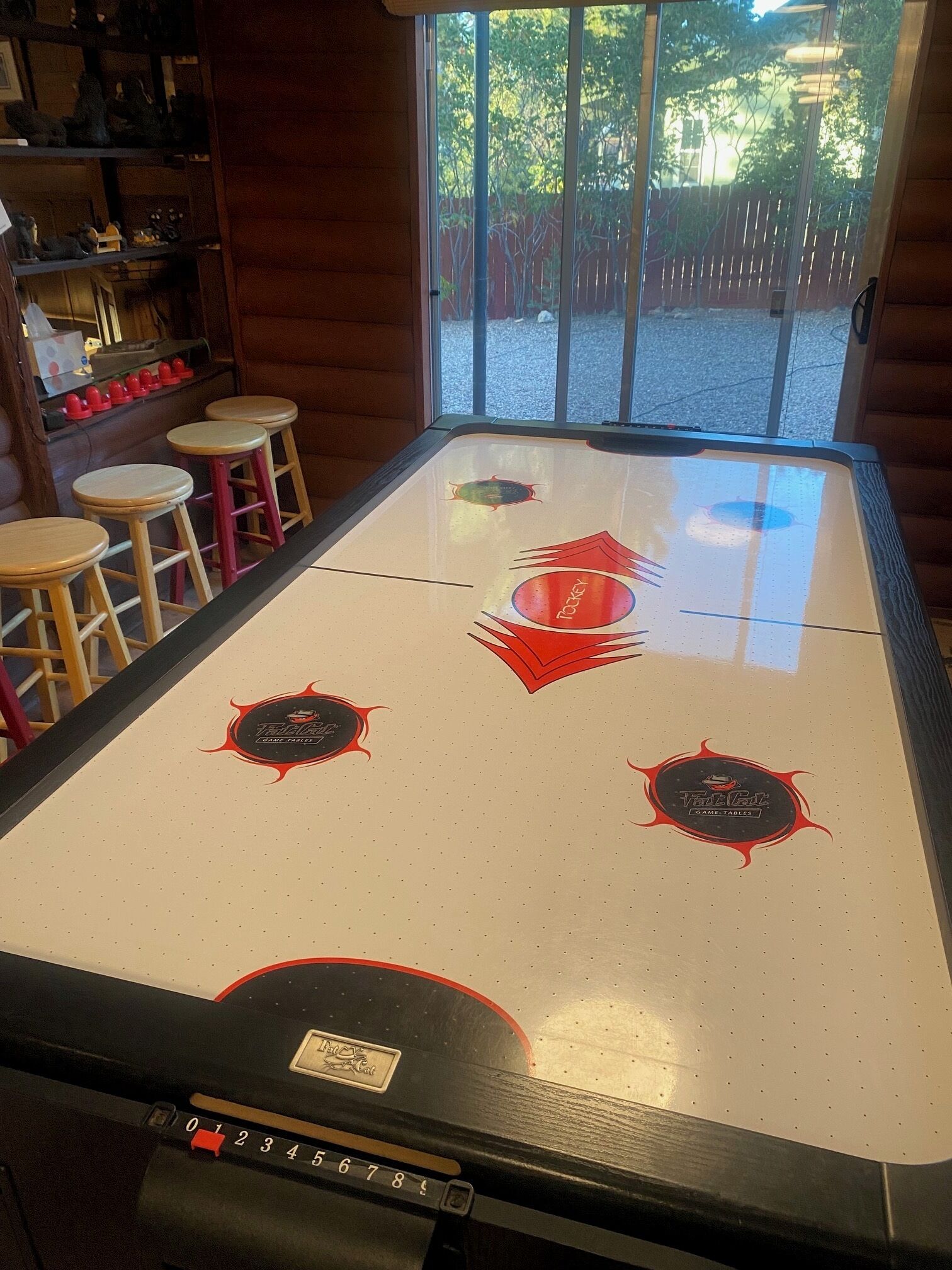 Une table de billard ornée d’un logo, des tabourets et une vue sur l’extérieur.