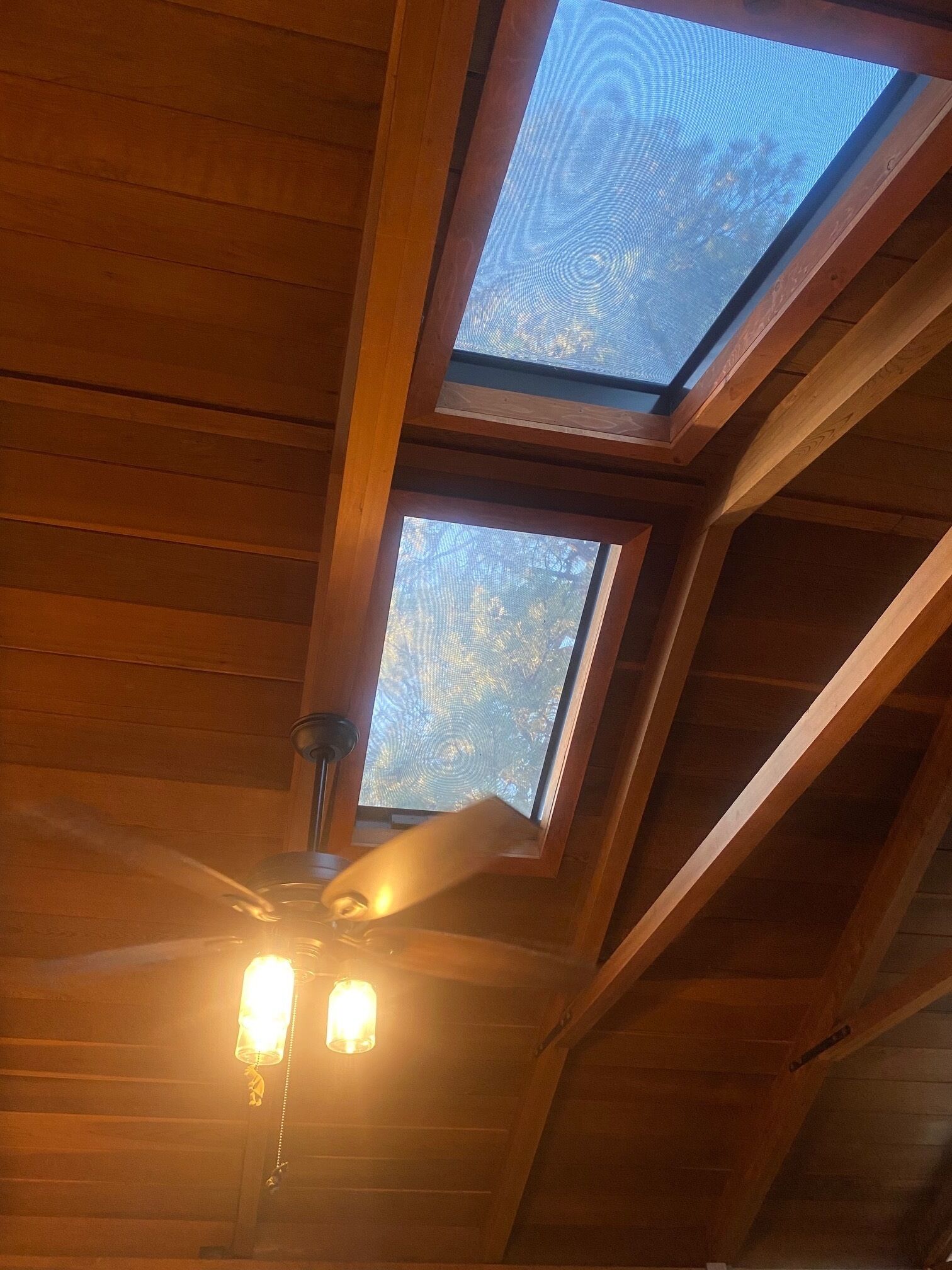 Um claraboia com teto de madeira e ventoinha.
