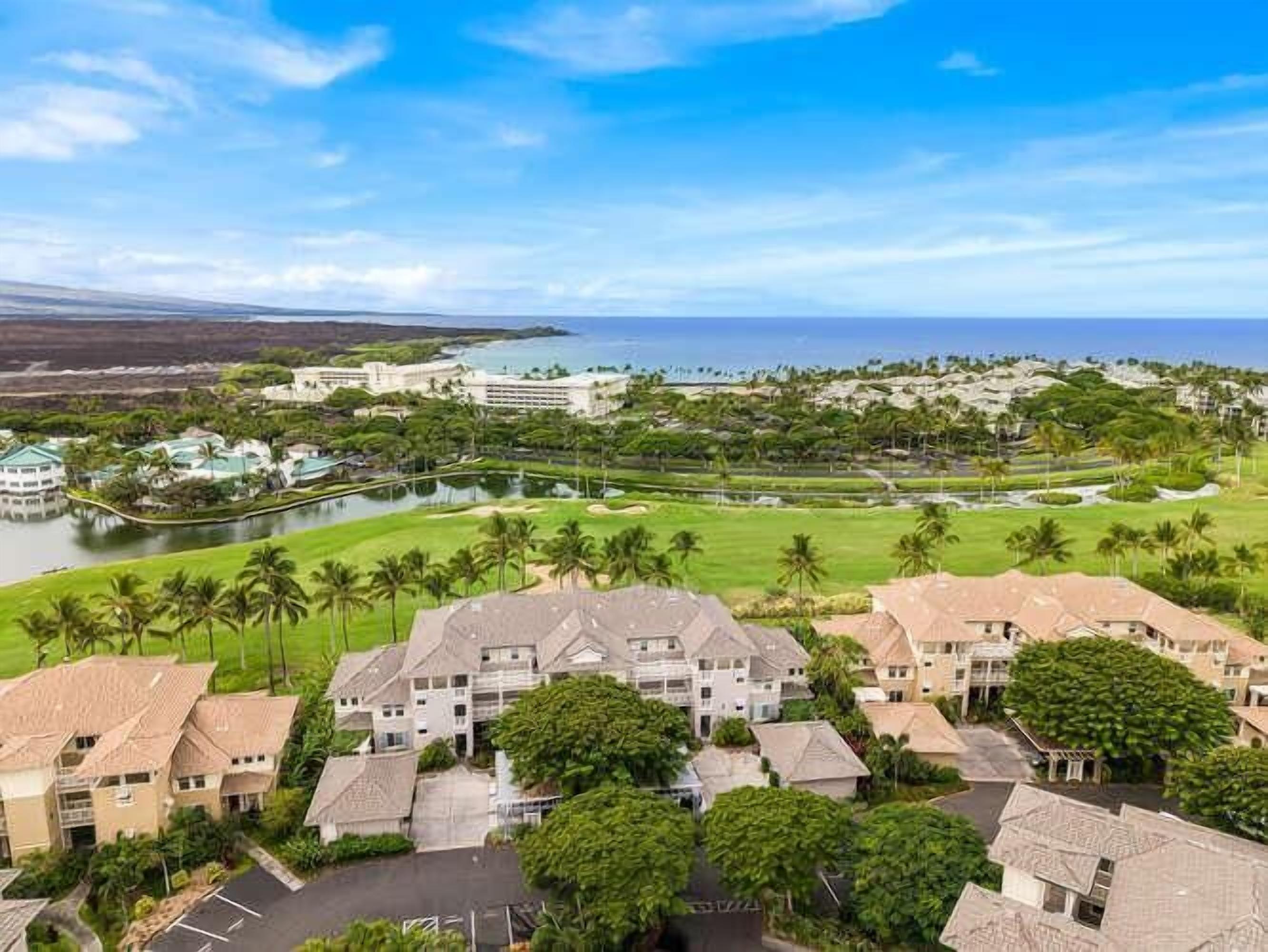 Un resort con diversi edifici, un campo da golf e una distesa d'acqua.