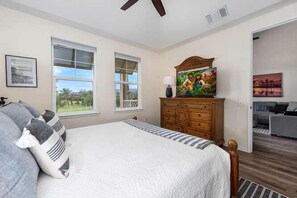 Une chambre à coucher avec un grand lit, une commode en bois et un tableau accroché au mur.