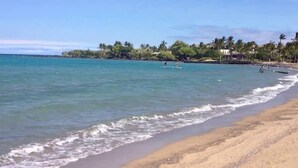 A beach with clear turquoise water, a sandy shore, and palm trees in the background. - Fairway Villas Waikoloa G31 (Waikoloa)