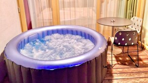 An inflatable hot tub with a blue light, a table, and a chair on a wooden deck.