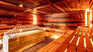A sauna with wooden walls and benches, a central heated bench, and a metal railing.