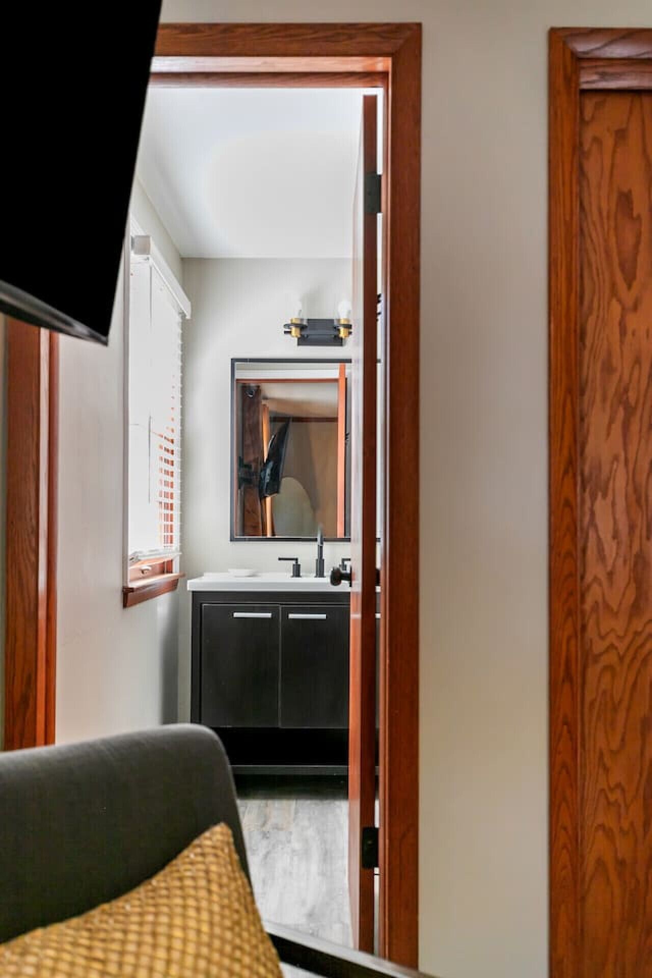 Un pasillo que conduce a un baño con espejo, lavamanos y armarios.
