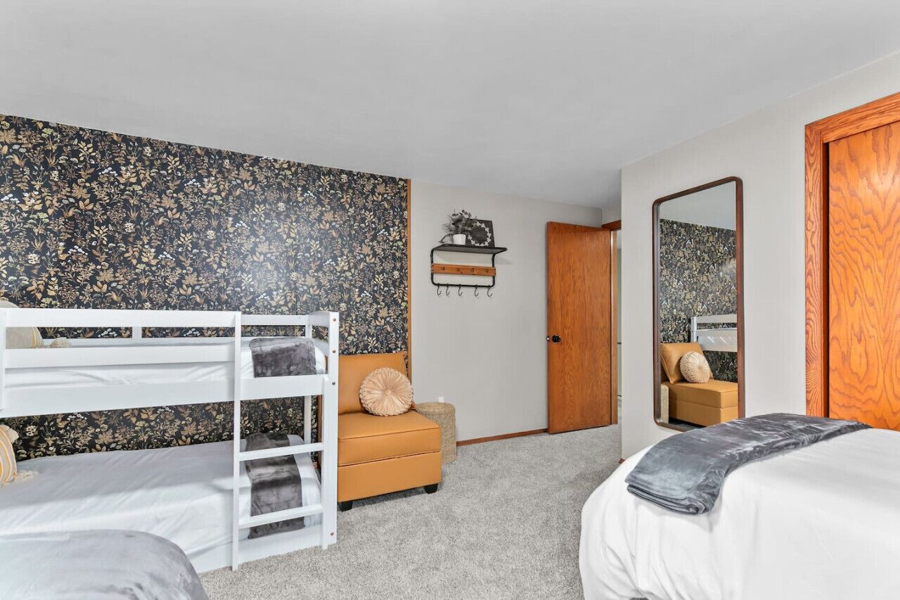 Une chambre avec un lit superposé, un canapé, une petite table et un miroir.