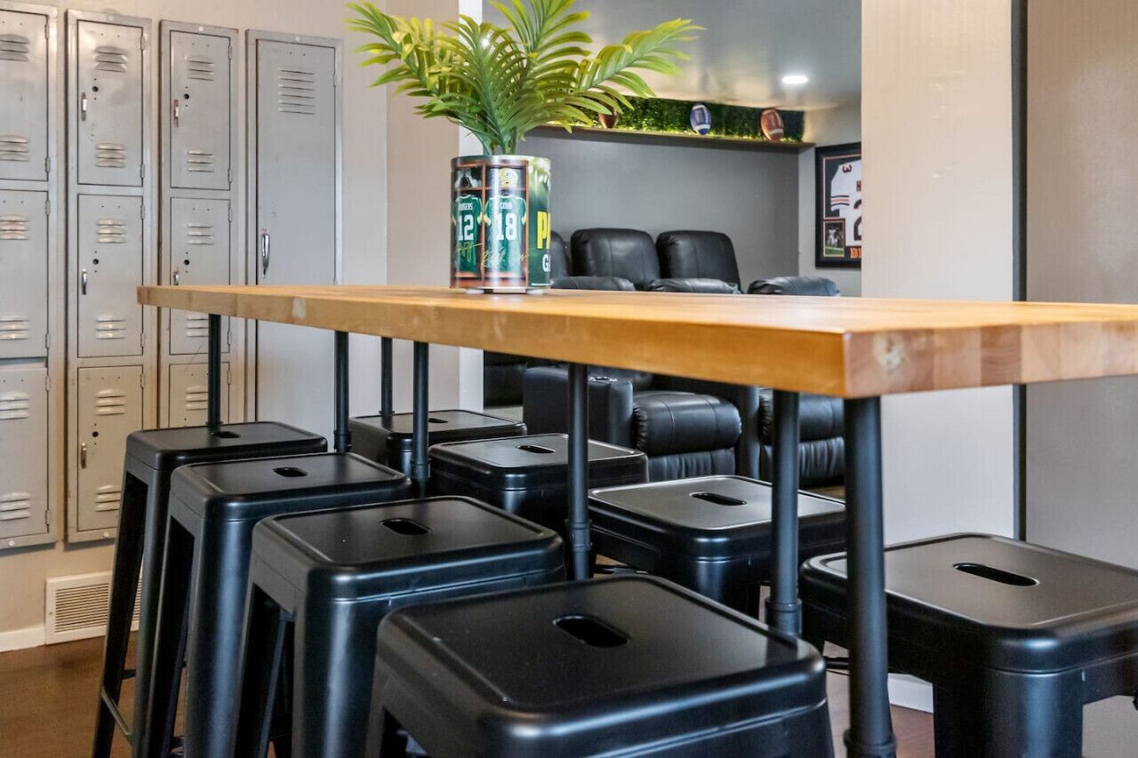 Une salle de conférence avec une longue table en bois, des tabourets noirs et une plante en pot posée sur la table.