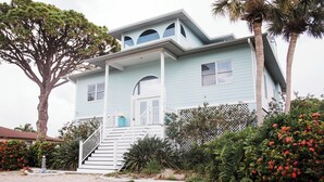 A light blue two-story house with a front porch, a staircase, and a large tree in the background. - Luxurious Large Home on Gulf of Mexico w/Private 30' Dock (Englewood)