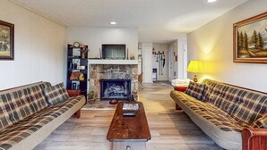 A cozy living room with two plaid sofas, a fireplace, a coffee table, and a bookshelf. - Cozy Mountain Retreat: Single-Level Condo in Sugar Mountain with Modern Comforts (Sugar Mountain)