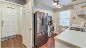 A modern kitchen with stainless steel appliances, a white countertop, and a window providing natural light. - Our Li'l Getawave! Two-bedroom condo in Pawleys Plantation Golf and Country Club (Pawleys Island)