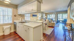 A spacious kitchen with white cabinets, a central island, and a dining area with a table and chairs. - Our Li'l Getawave! Two-bedroom condo in Pawleys Plantation Golf and Country Club (Pawleys Island)