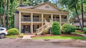 A two-story house with a porch, a staircase, and a front door. - Our Li'l Getawave! Two-bedroom condo in Pawleys Plantation Golf and Country Club (Pawleys Island)
