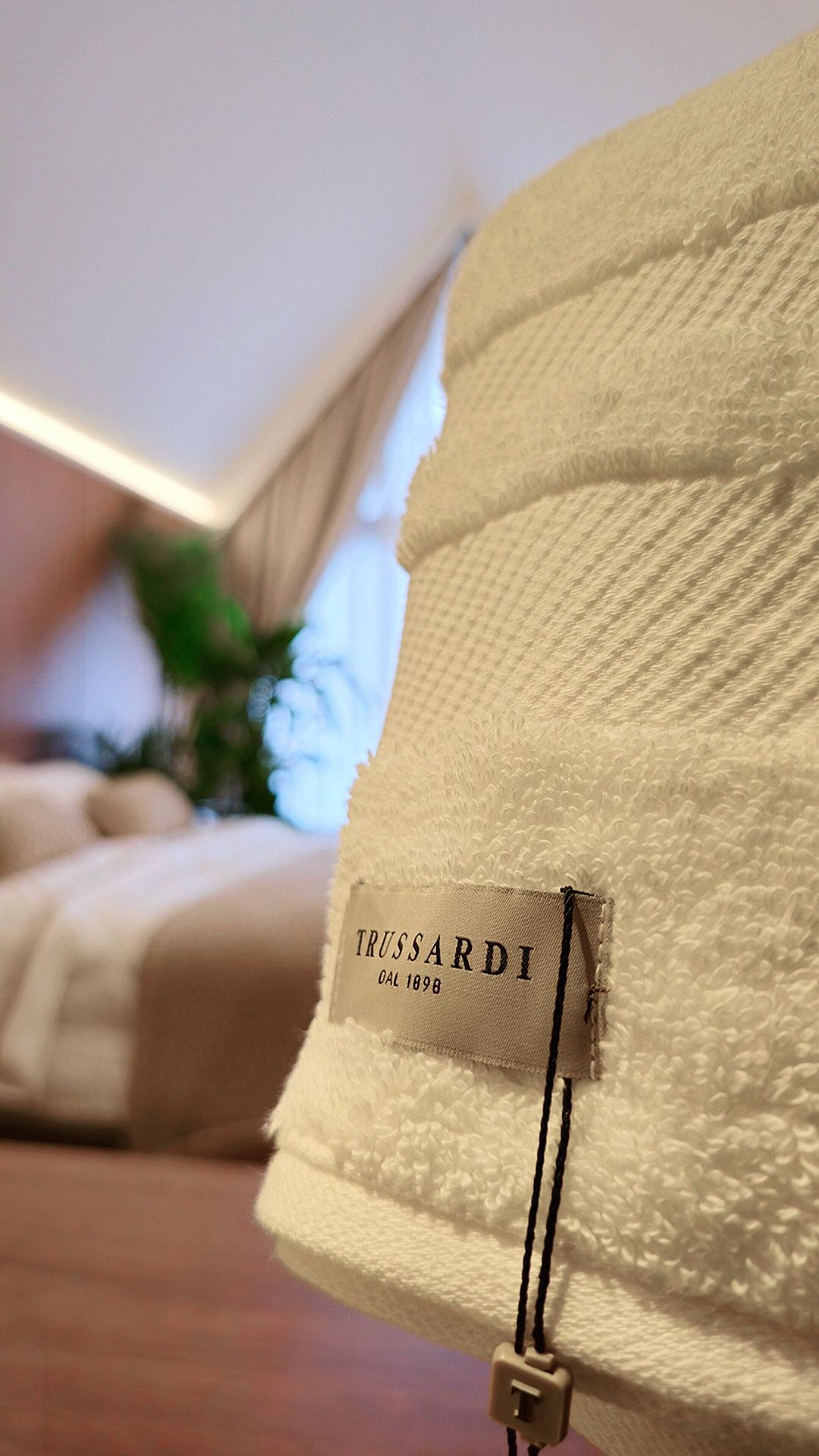 Gros plan d’un tissu doux et texturé, agrémenté d’une étiquette indiquant « TRUSSARDI » et « DAL 1898 ».