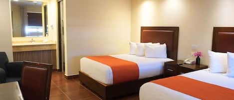 Una habitación de hotel con dos camas, baño y comedor.