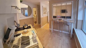 A modern kitchen with a dining area, a large mirror, and a TV mounted on the wall. - The White cosy, maxi studio in the city center, 1 km from the train station, tourism/business (Calais)