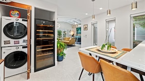 Une cuisine moderne dotée d’appareils électroménagers intégrés, un coin repas avec une table et des chaises, et une vue sur l’extérieur.