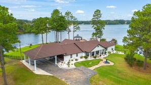 A large house with a covered patio, a swimming pool, and a view of a lake.