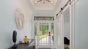 A hallway with a black console, a decorative wall piece, and a sliding glass door leading to a garden.