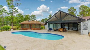 A modern house with a swimming pool, a covered patio, and a basketball court.