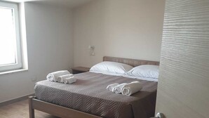 A neatly made bed with rolled towels, a wooden headboard, and a wooden floor. - Panoramik  (Acri)
