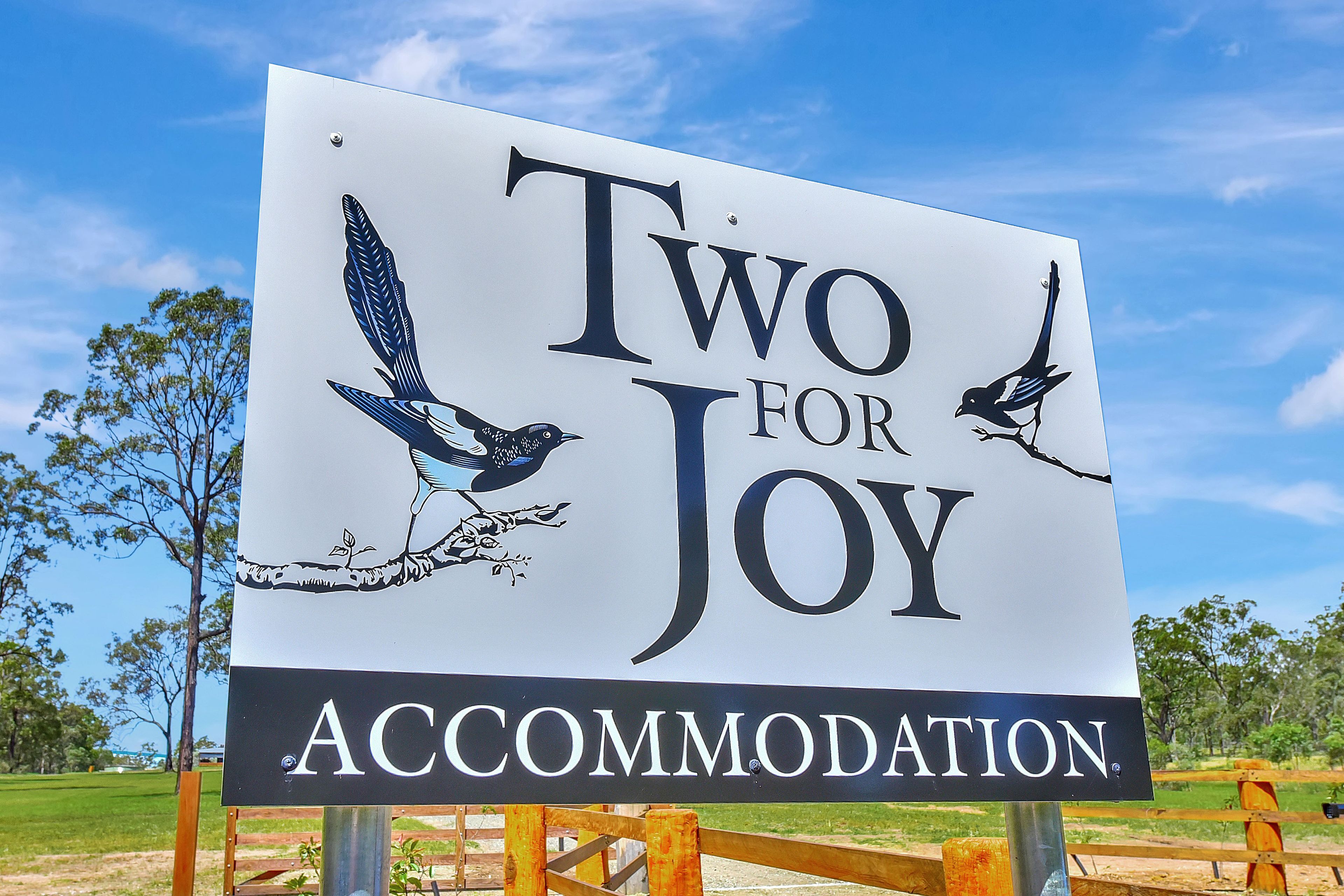 Une enseigne portant l’inscription « Two for Joy Accommodation » et illustrée d’images d’oiseaux.