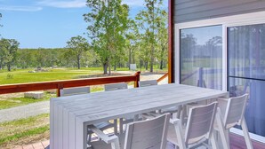 An outdoor patio with a table and chairs, overlooking a grassy area with trees. - Magpie 2 3 Two for Joy Estate. 3 bedroom (North Rothbury)