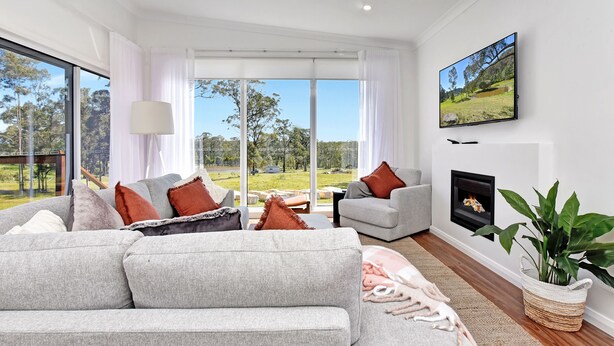 A modern living room with a grey sofa, a flat-screen TV, and a fireplace. - Magpie 2 3 Two for Joy Estate. 3 bedroom (North Rothbury)