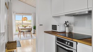 Una cuina moderna amb armaris blancs, tauleig de fusta, microones i forn.