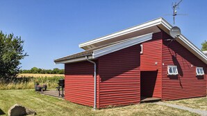 Un edifici vermell amb teulada inclinada, antena parabòlica i una finestra petita.