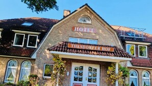 A hotel with a traditional brick facade, a prominent sign reading "HOTEL THESDORFER HOF," and a symmetrical entrance with double doors. - Hotel Thesdorfer Hof (Pinneberg)