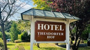 A sign for Hotel Thesdorf Hof with a white structure and a brown signboard. - Hotel Thesdorfer Hof (Pinneberg)