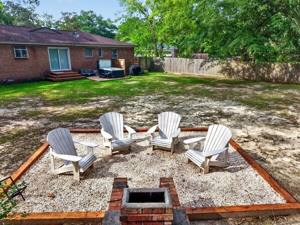 Um quintal com quatro cadeiras Adirondack dispostas ao redor de um braseiro.