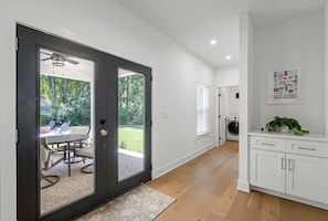A modern interior with a sliding glass door leading to an outdoor patio, a kitchen area with white cabinetry, and a ceiling fan.