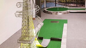 A miniature golf course with a green putting surface, a yellow golf ball, and a metal basket. - Welcoming Holiday Home With Terrace (Aabenraa)