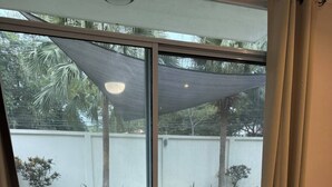 Une chambre dotée d’une grande porte-fenêtre coulissante donnant sur une terrasse avec piscine et mobilier d’extérieur.