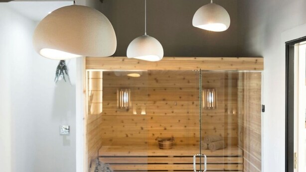 Un intérieur moderne avec des murs lambrés en bois, une cloison en verre et des luminaires suspendus.