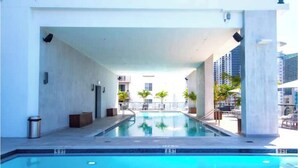 Una piscina interior moderna con agua azul cristalina, rodeada por un edificio blanco con un paseo techado.