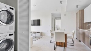 Una cocina moderna con armarios blancos, encimera de madera y horno empotrado.